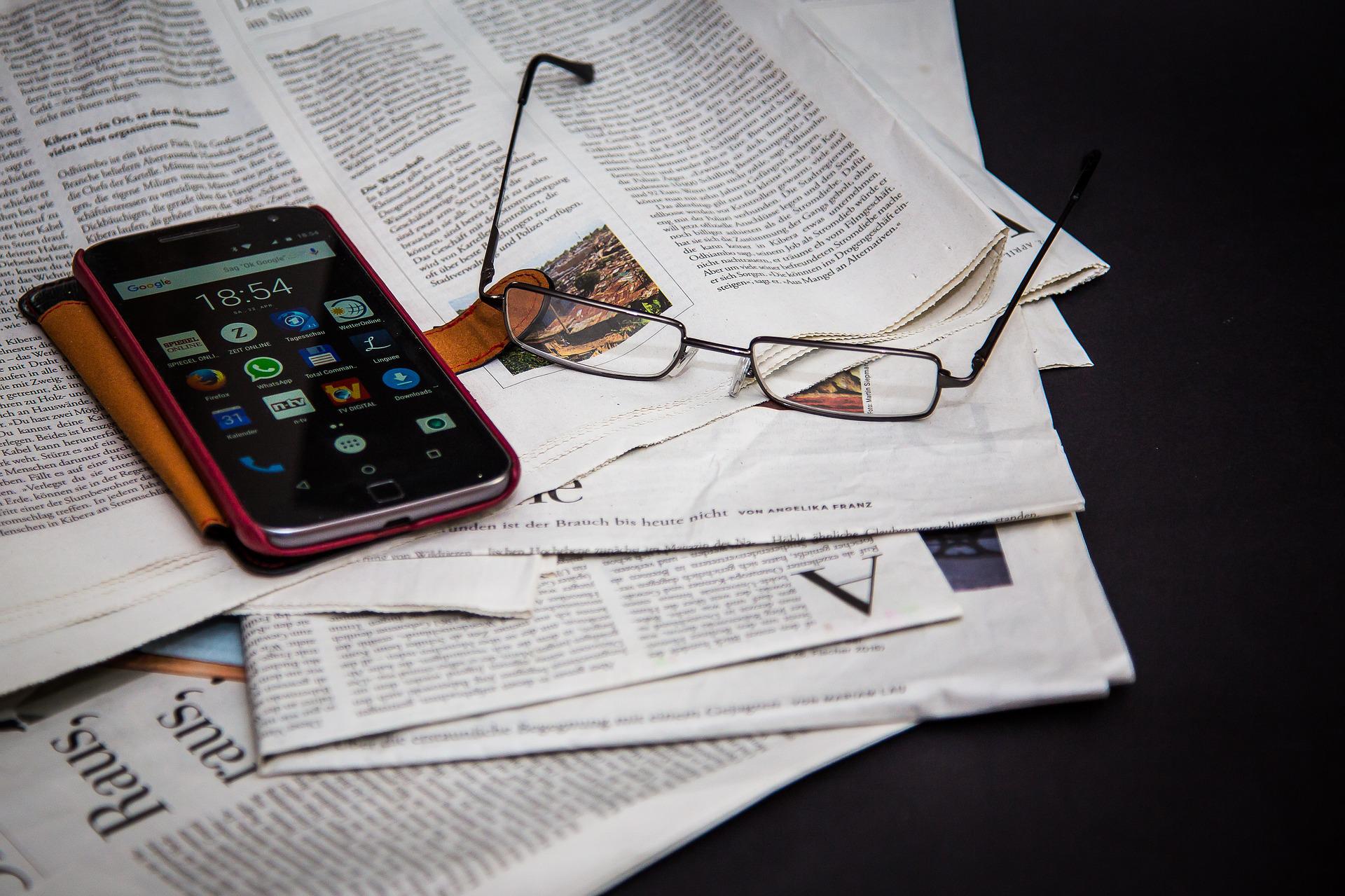 Newspaper, phone and glasses