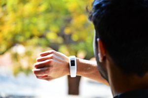 Man checking a wearable tracker device to monitor his health